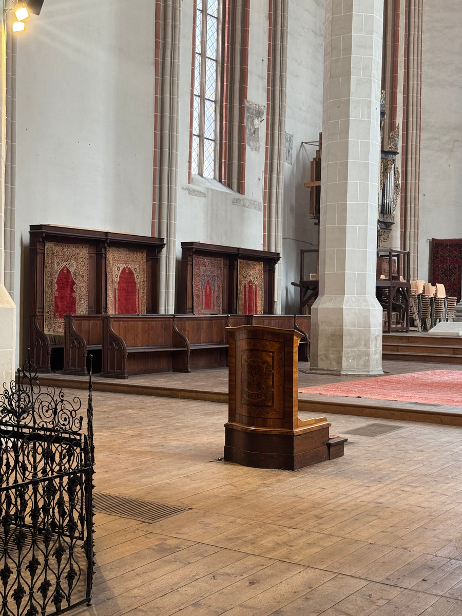 Ottoman prayer-format rugs displayed beside the wooden pews inside the Black Church in Brașov